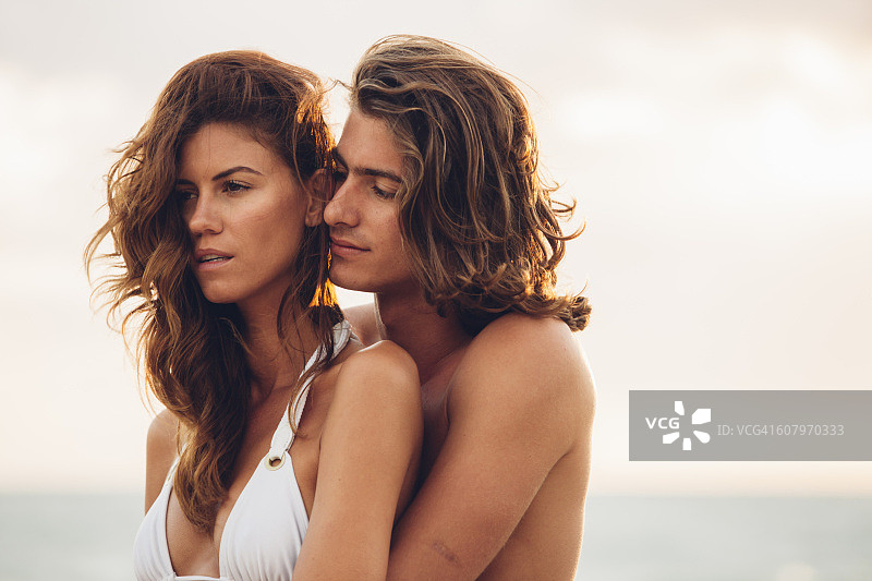 浪漫的年轻情侣在海滩上相互拥抱图片素材