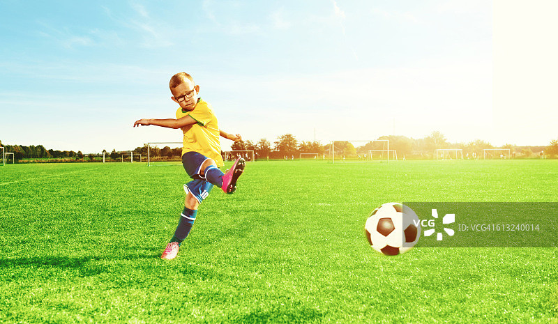 男孩踢足球，在操场上踢球图片素材