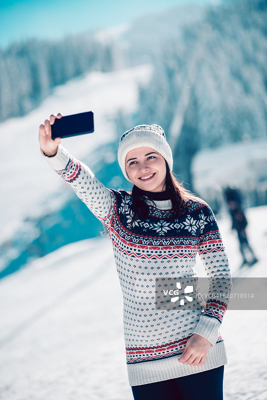 微笑的女孩享受冬天，在下雪的时候自拍图片素材