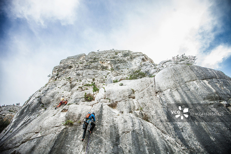 低角度后视图的攀岩者爬上山坡，奥格里亚斯特，撒丁岛，意大利图片素材