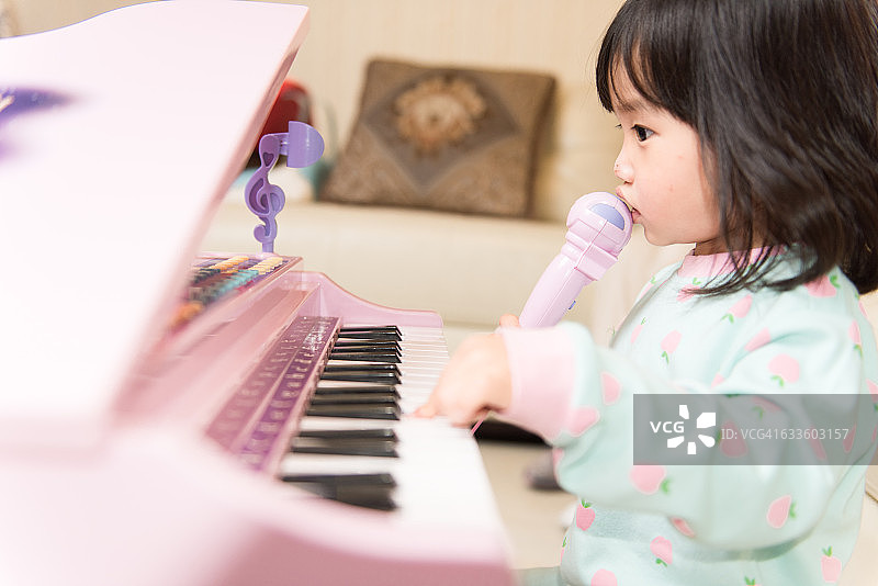 孩子在家里玩玩具钢琴，快乐地唱歌图片素材