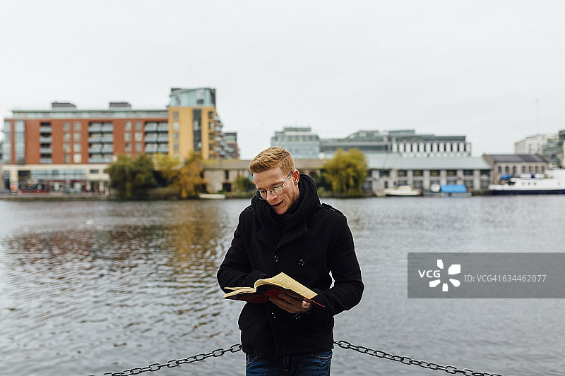 爱尔兰，都柏林，一个年轻人在水边看书图片素材