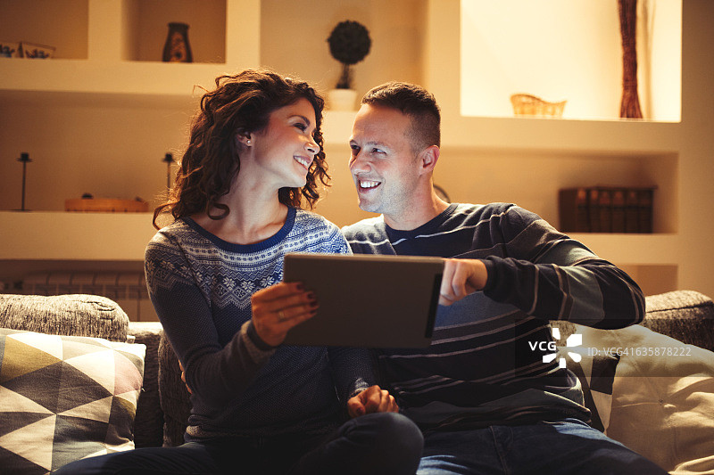 一对深情的情侣正在家里休息，用着数码平板电脑。图片素材