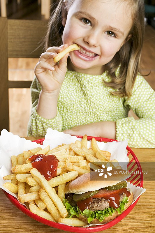 女孩吃薯条和番茄酱和汉堡图片素材