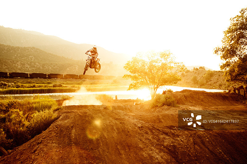 夕阳西下，男子跳上越野摩托车。图片素材