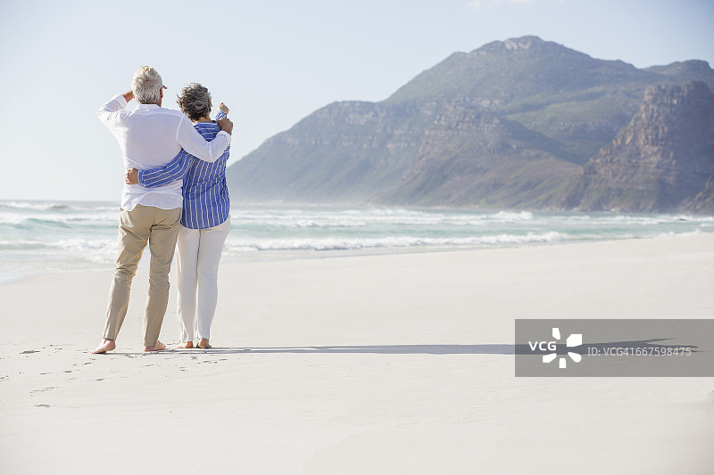一对夫妇的后视图，手挽着手站在海滩上图片素材