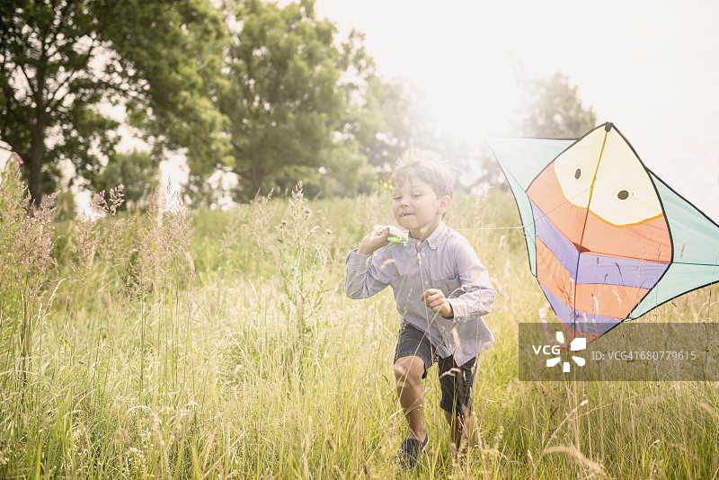 德国巴伐利亚，一个小男孩带着风筝在草地上奔跑图片素材