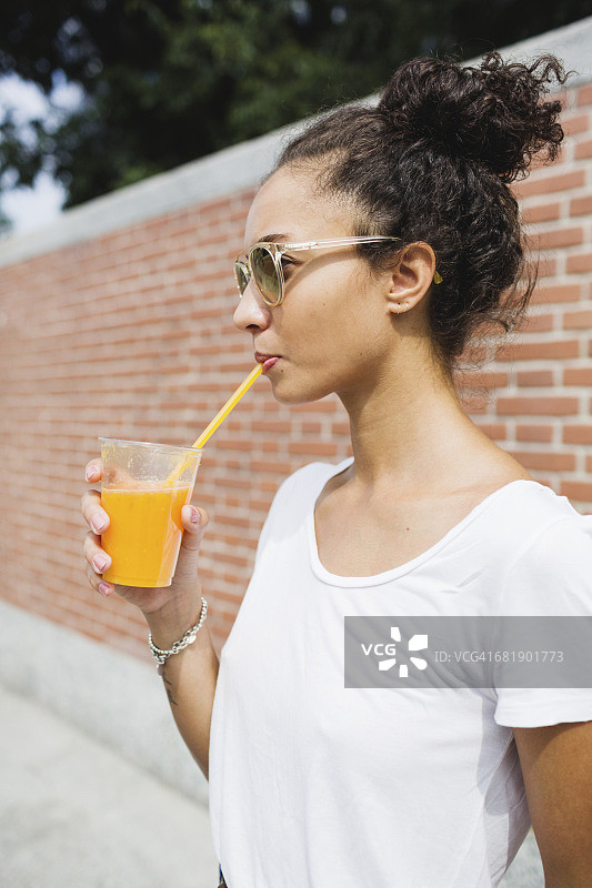 年轻女子在户外喝橙汁图片素材