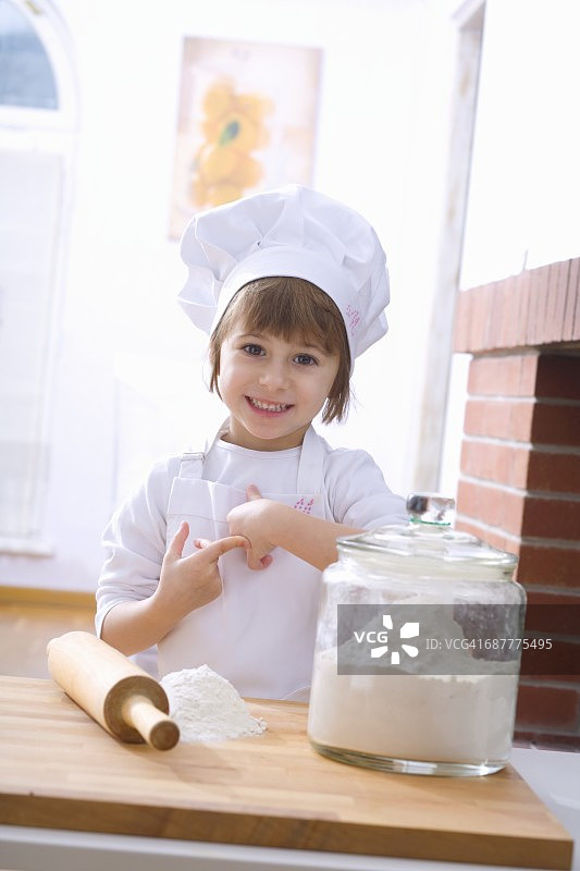 小女孩戴着厨师帽，带着面粉和擀面杖图片素材