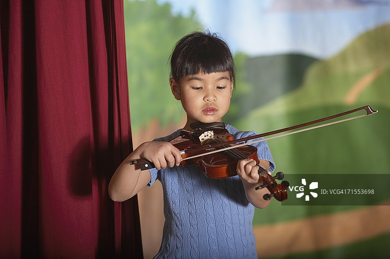 年轻的亚洲女孩在独奏会拉小提琴图片素材