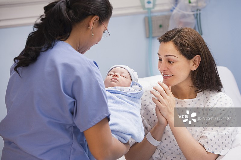 女护士将新生儿交给母亲图片素材