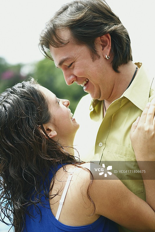 一个年轻女子和一个中年男子微笑着拥抱在一起的侧影图片素材