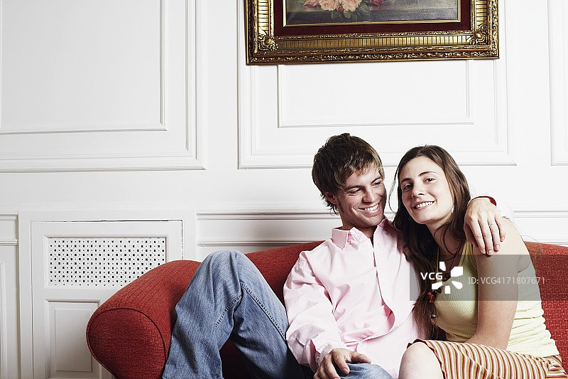一对年轻夫妇坐在沙发上的肖像图片素材