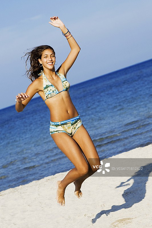 少女在沙滩上蹦蹦跳跳图片素材