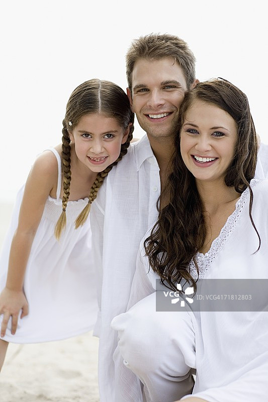 一对年轻夫妇和他们的女儿微笑的肖像图片素材