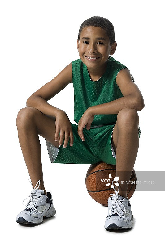 一个男孩坐在篮球上的肖像图片素材