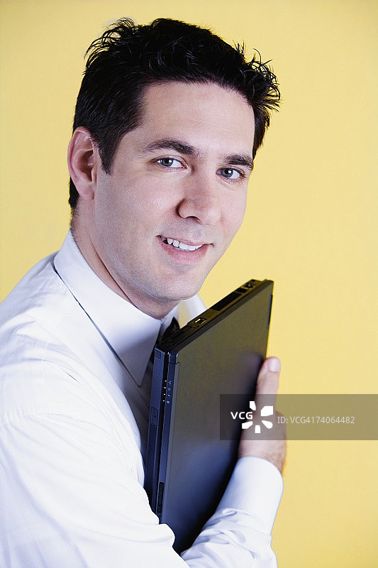 一个微笑着拿着笔记本电脑的商人的肖像图片素材