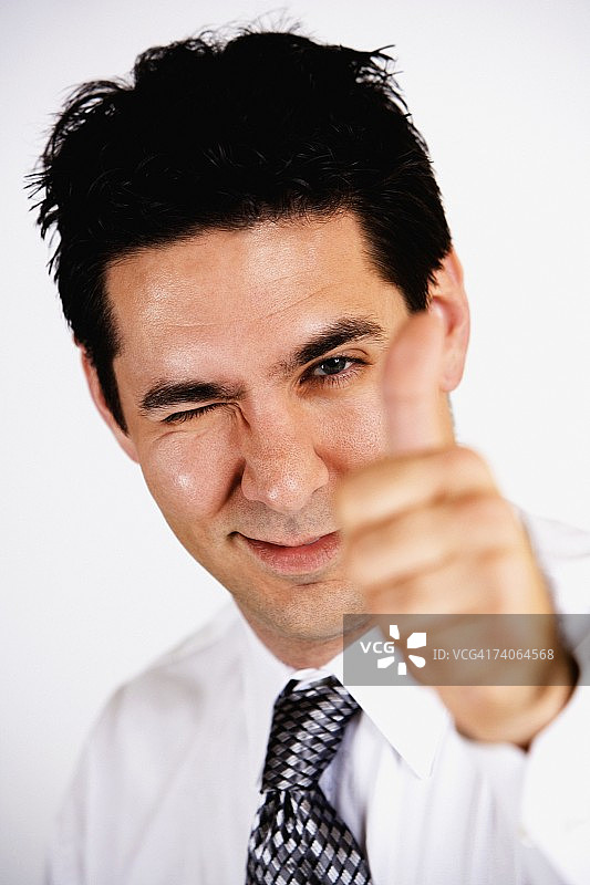一个商人做拇指竖起的手势和眨眼的肖像图片素材