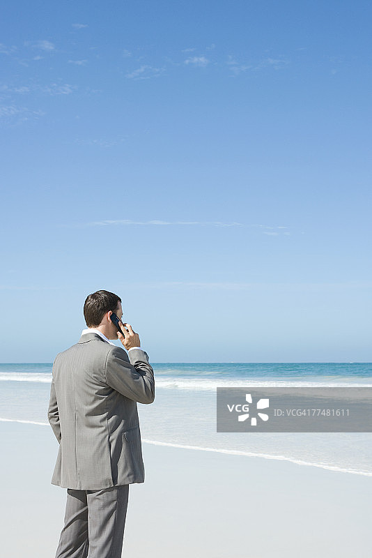 商人站在沙滩上，用手机打电话图片素材