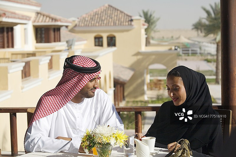 阿拉伯夫妇在阳台上喝咖啡。阿拉伯联合酋长国迪拜图片素材