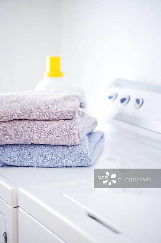 折叠毛巾和洗涤剂放在白色洗衣机和烘干机上图片素材