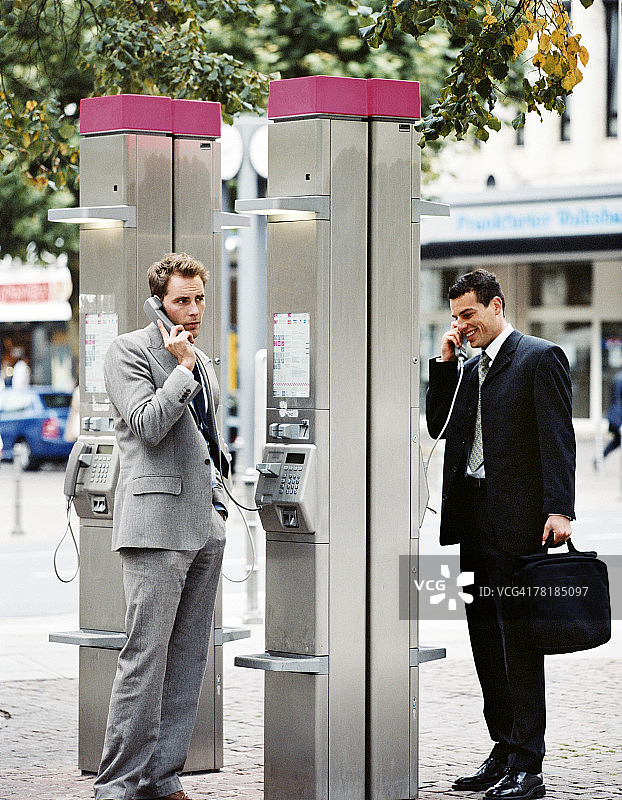 在公用电话前交谈的商人图片素材
