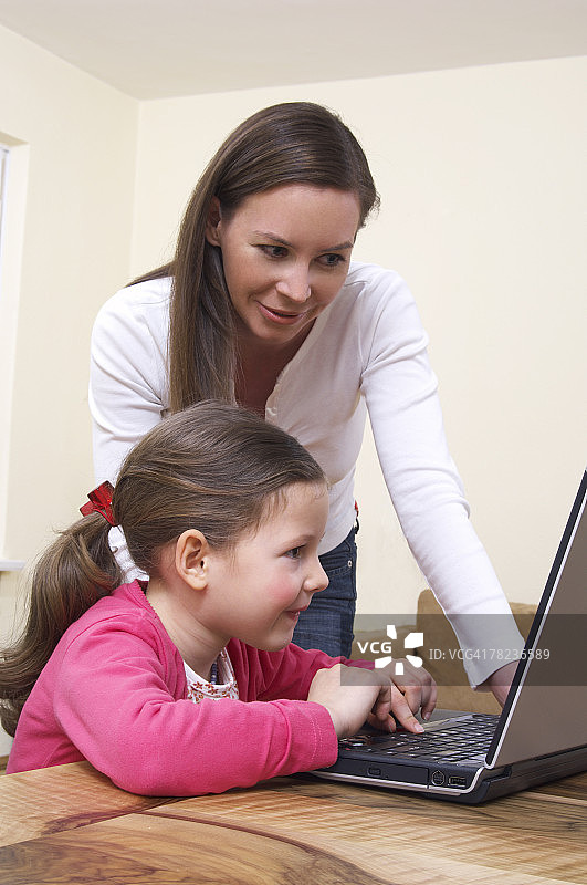 年轻的母亲教小女儿如何使用笔记本电脑图片素材