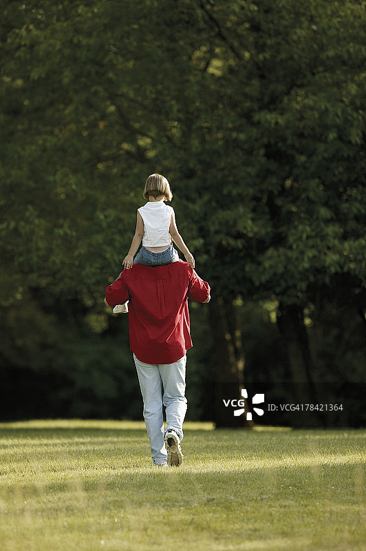 在公园里，女儿骑在父亲的肩膀上图片素材