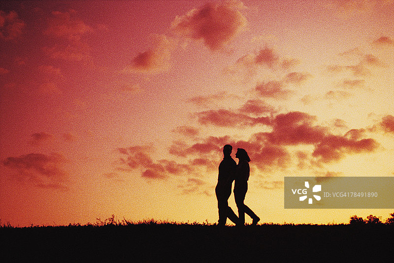 黄昏中散步的情侣剪影图片素材