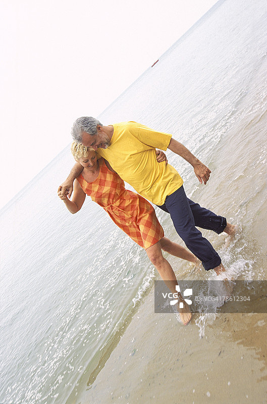 顽皮的情侣一起沿着海滩散步图片素材