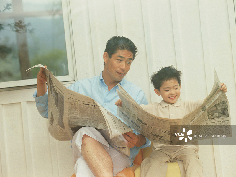 父亲和儿子在看报纸图片素材