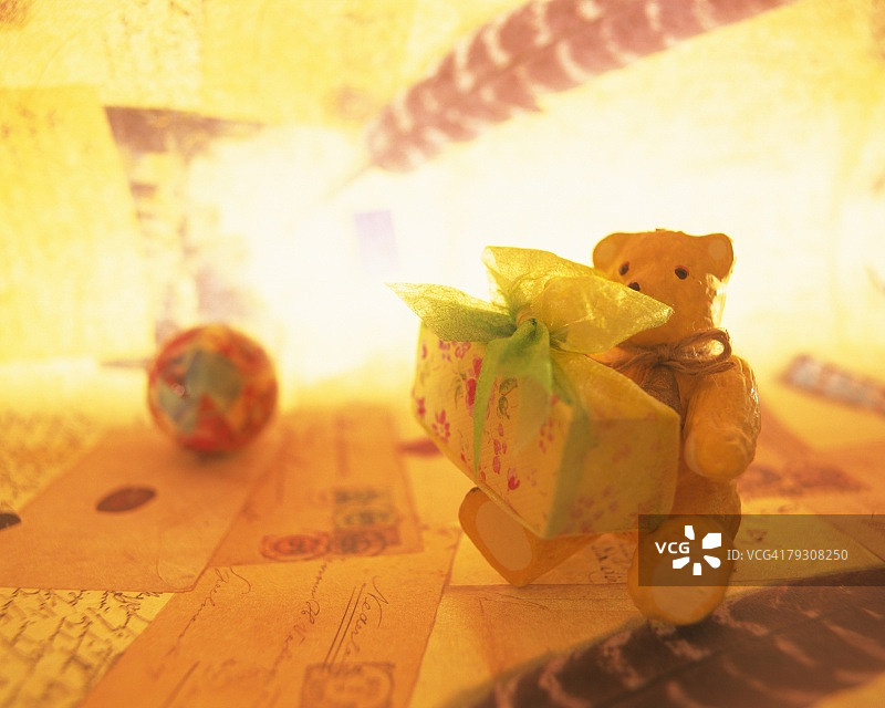 泰迪熊拿着一个装着礼物的盒子，坐在圣诞卡上，正面看图片素材