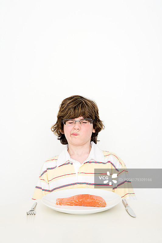 一个男孩拿着一盘鲑鱼图片素材