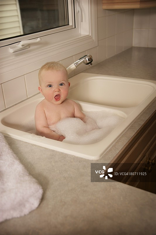 一个婴儿在厨房的水槽里洗澡图片素材