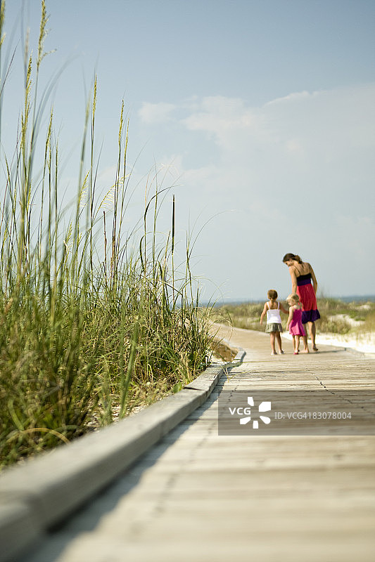 母亲和女儿在海滨木板路散步图片素材