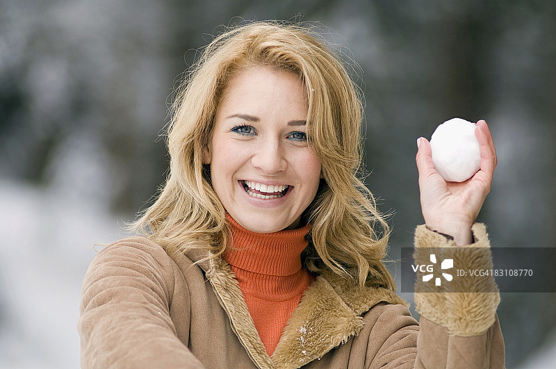 奥地利，萨尔茨堡国，阿尔滕马克，一名年轻女子捧着一个雪球，微笑着，肖像图片素材