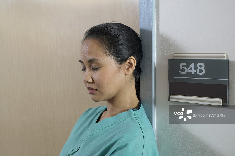 一个年轻的女护士在医院里靠墙睡觉的肖像图片素材