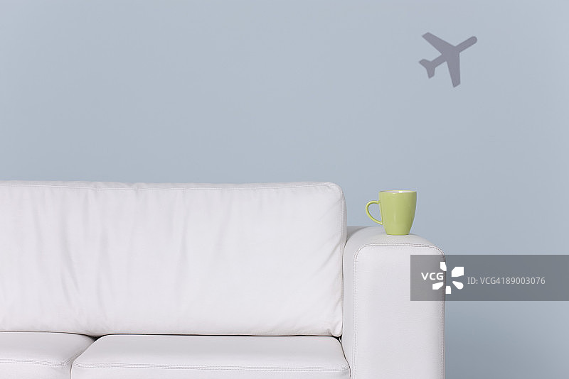 沙发扶手上的杯子，背景是飞机形状图片素材