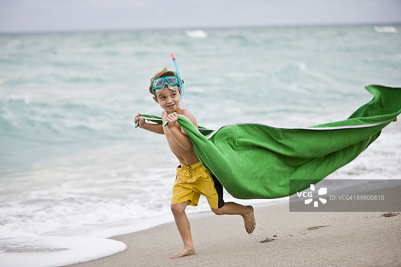 男孩戴着潜水面罩在海滩上跑步图片素材