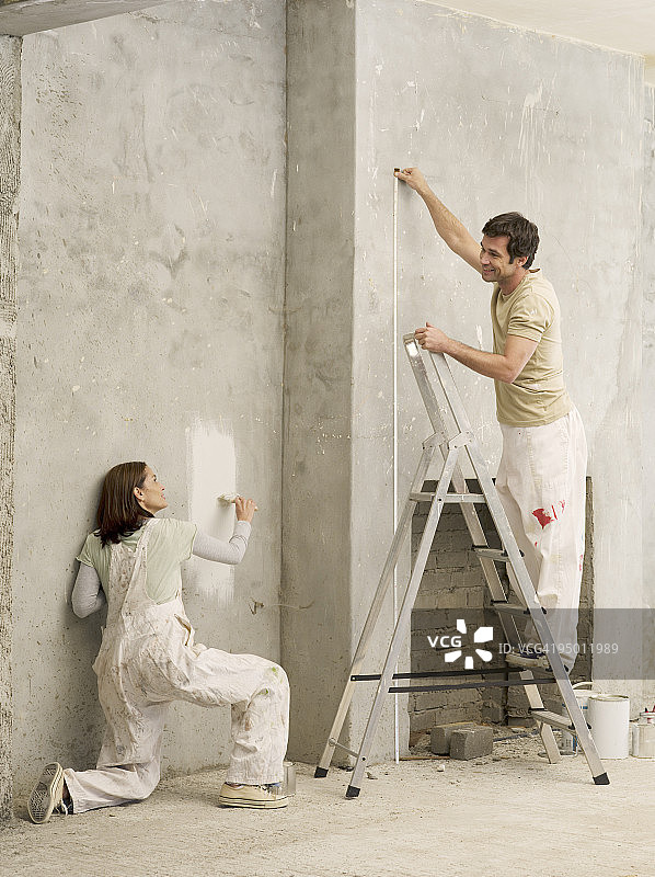 一对丈量和粉刷客厅墙图片素材