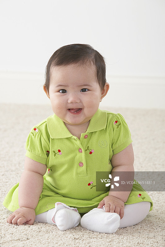 亚洲婴儿微笑地坐在地板上图片素材