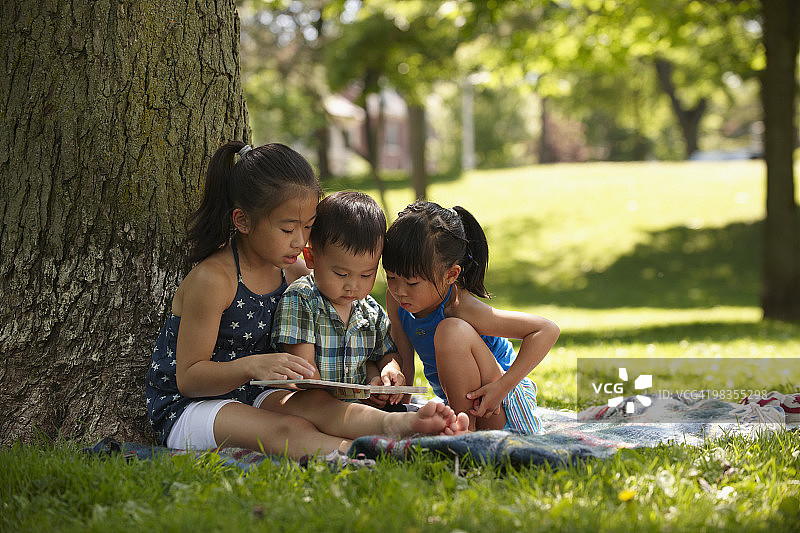 中国孩子在公园里读故事书图片素材