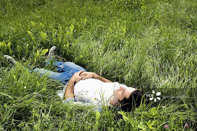 在草地上打瞌睡的年轻人的全身画像图片素材