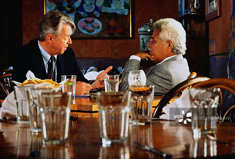 两位成熟的商人坐在餐厅里聊天图片素材