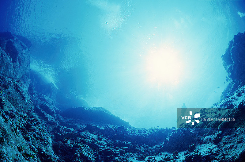 阳光照在岩石表面，潜水员在远处，水下风景图片素材