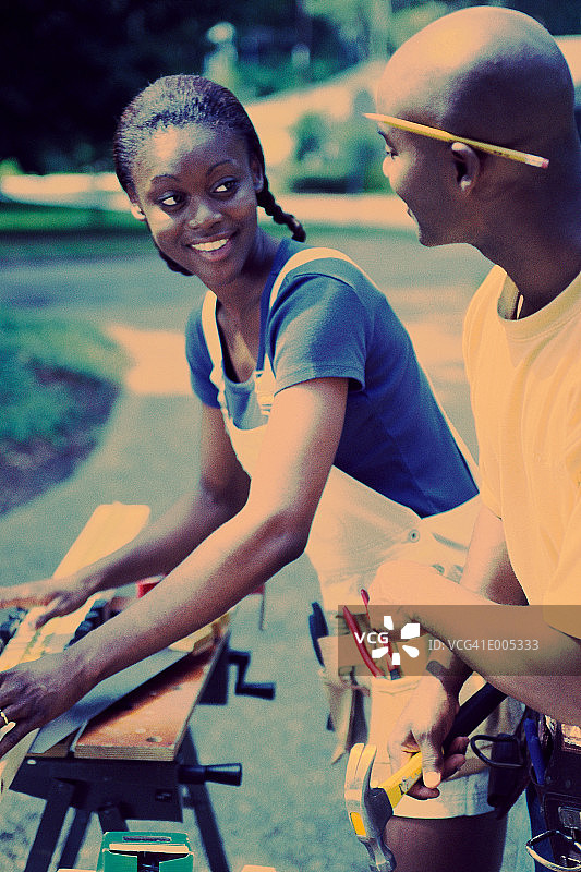一对非裔美国夫妇在户外用电锯图片素材