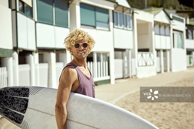 在夏天的海滩上，微笑着的男人拿着冲浪板图片素材