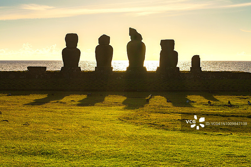 复活节岛——巨人站在阿胡塔海的摩埃石像上，身后是海面上的日落天空。图片素材