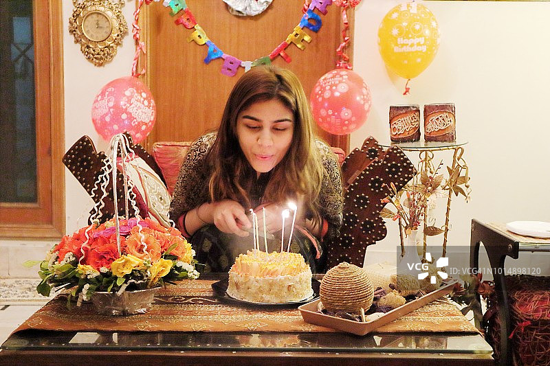 巴基斯坦女孩在切生日蛋糕前吹蜡烛图片素材