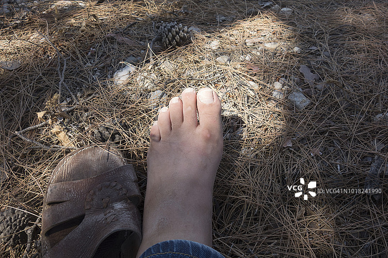 欧洲，希腊，2018:穿着定制皮革凉鞋的人坐在森林里(骆驼皮，北非)图片素材